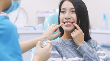 Woman pointing to her smile during preventive dentistry appointment