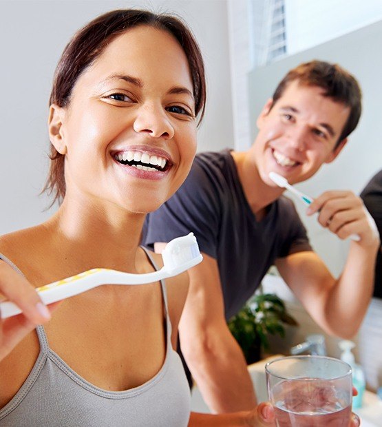 Man and woman brushing teeth after teeth whitening treatment