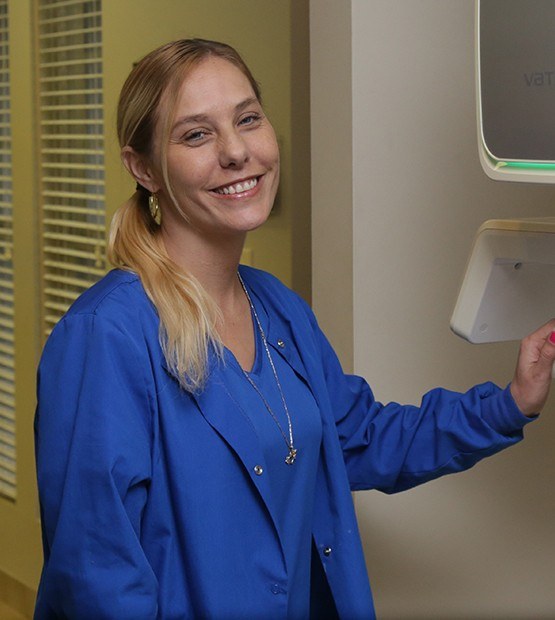 Dental team member smiling next to 3 D C T scanner