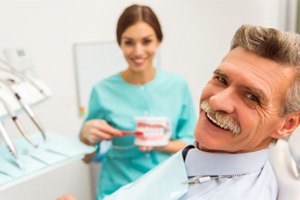 An older man with dentures seeing a dentist