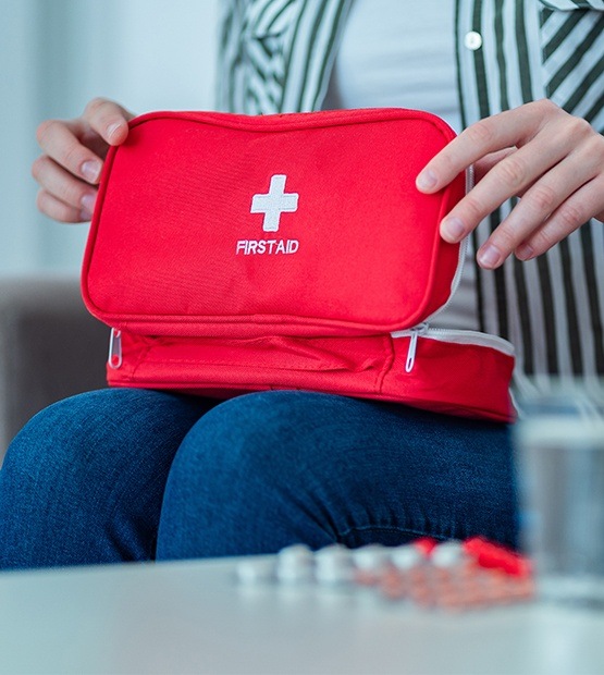 Person opening first aid kit with dental supplies