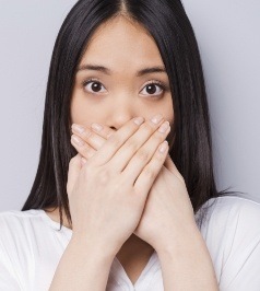 Woman with lost filling covering her mouth