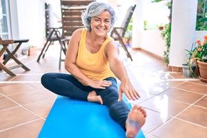 Healthy woman with dental implants in Flower Mound practicing yoga