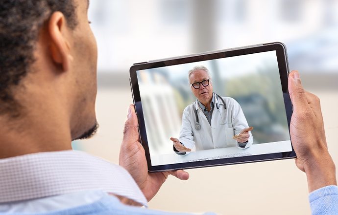 Man holding tablet while on video call with dentist