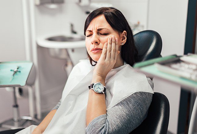 Woman in need of periodontal therapy holding jaw