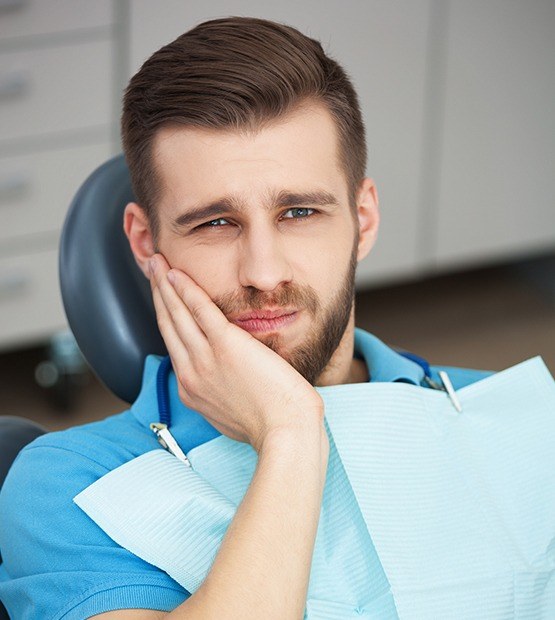 Man in need of root canal therapy holding cheek