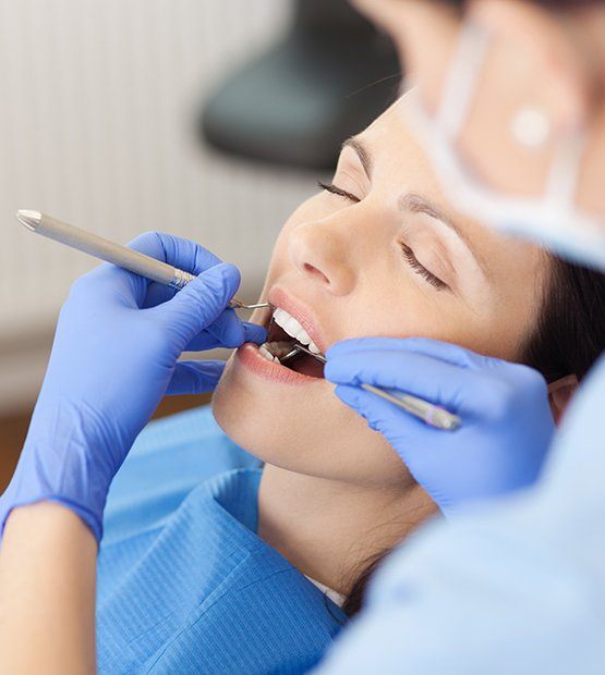 Woman under dental sedation receiving dentistry treatment