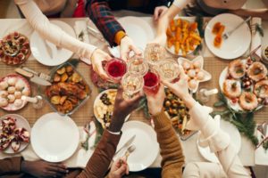 friends cheers-ing over a holiday dinner table