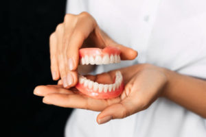 Upper and lower denture held in female’s hands